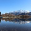 snowy mountains reflected in a lake with trees and a boat